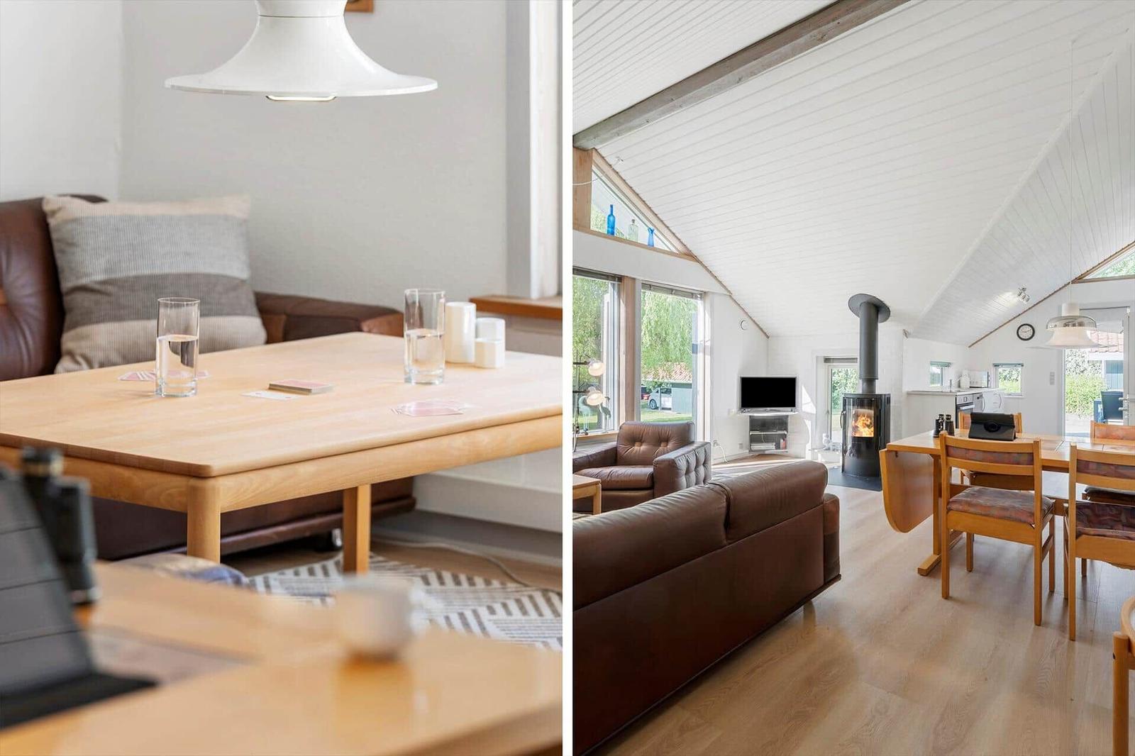 Living area with wooden table, leather sofa, and wood stove under high ceiling.