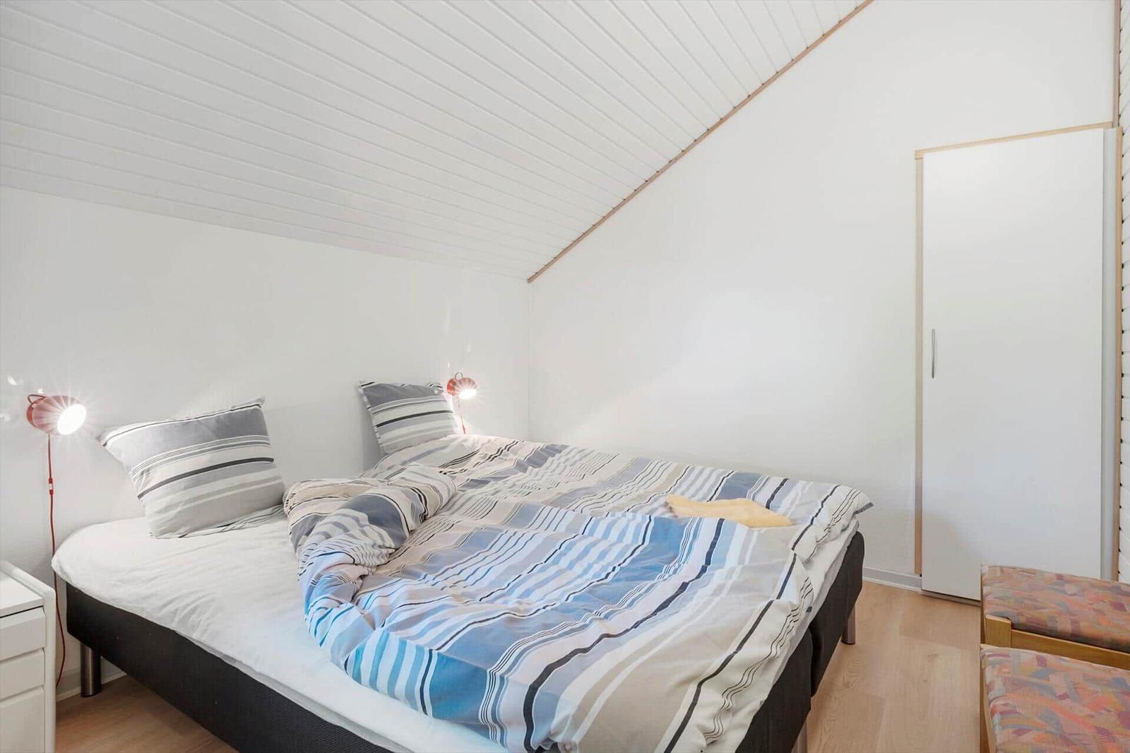 Bedroom with double bed, two bedside tables and wardrobe against the wall.