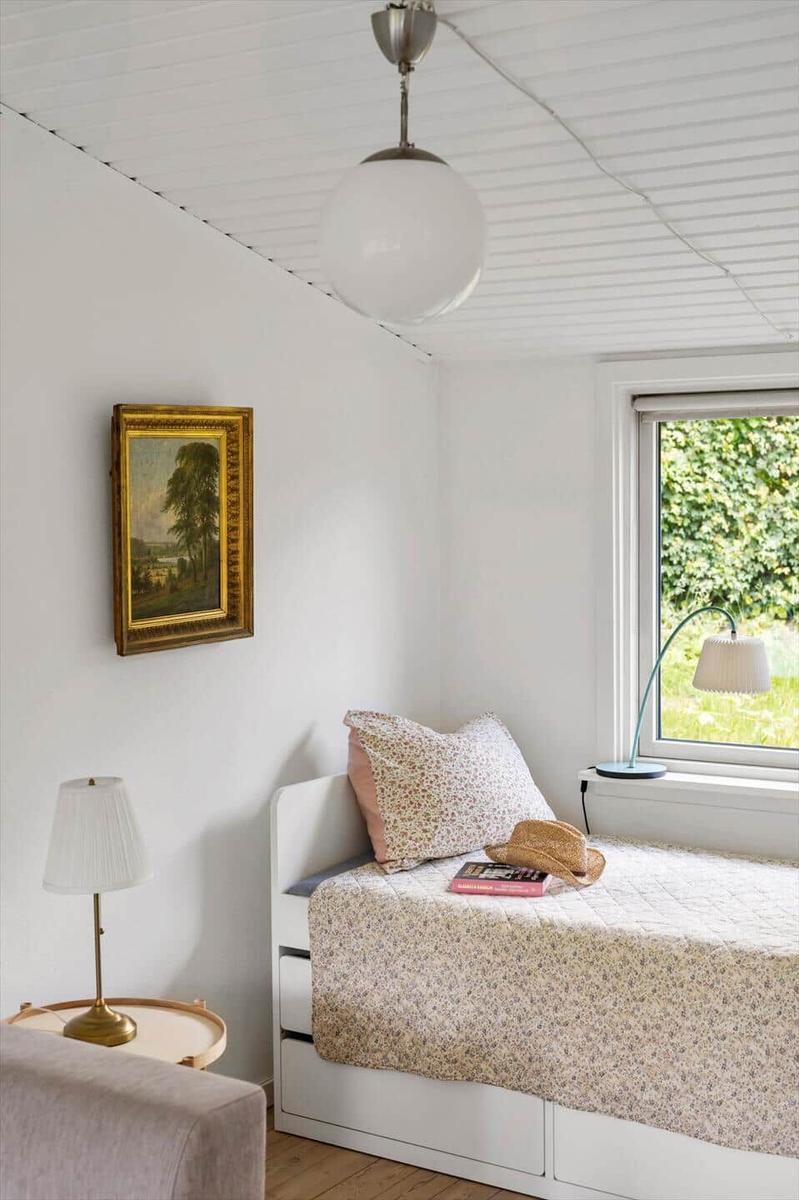 Bedroom with bed, window, lamp, and picture on the wall.