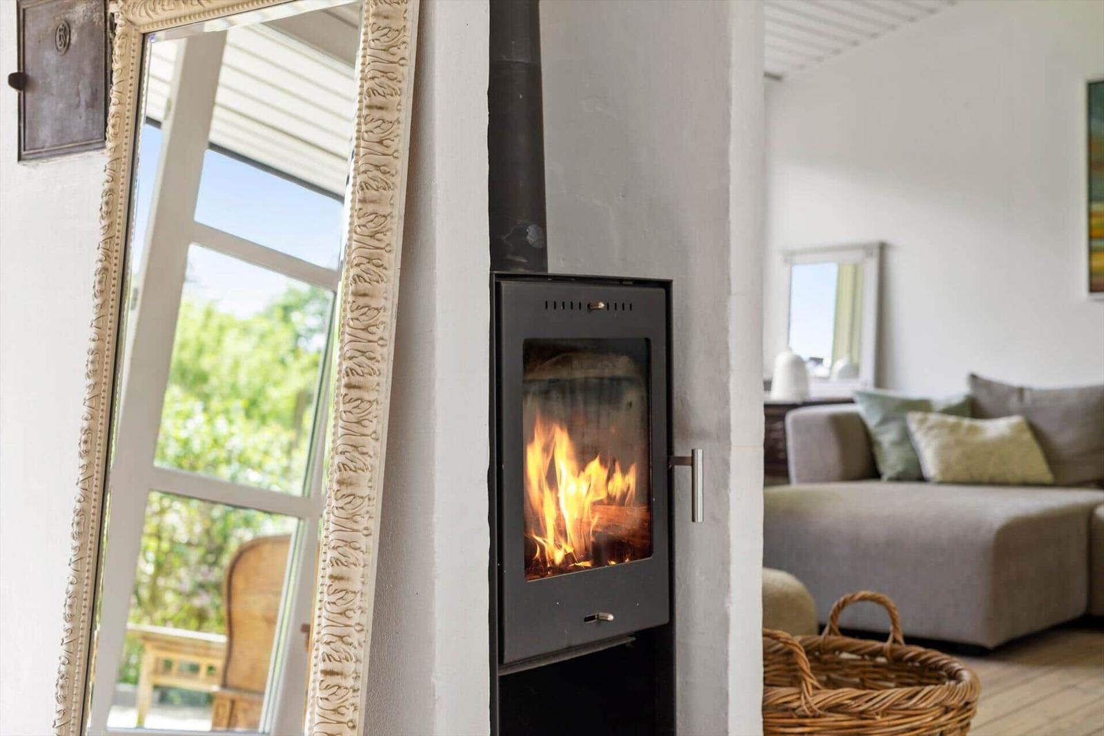 Wood-burning stove with fire in living room with sofa and mirror