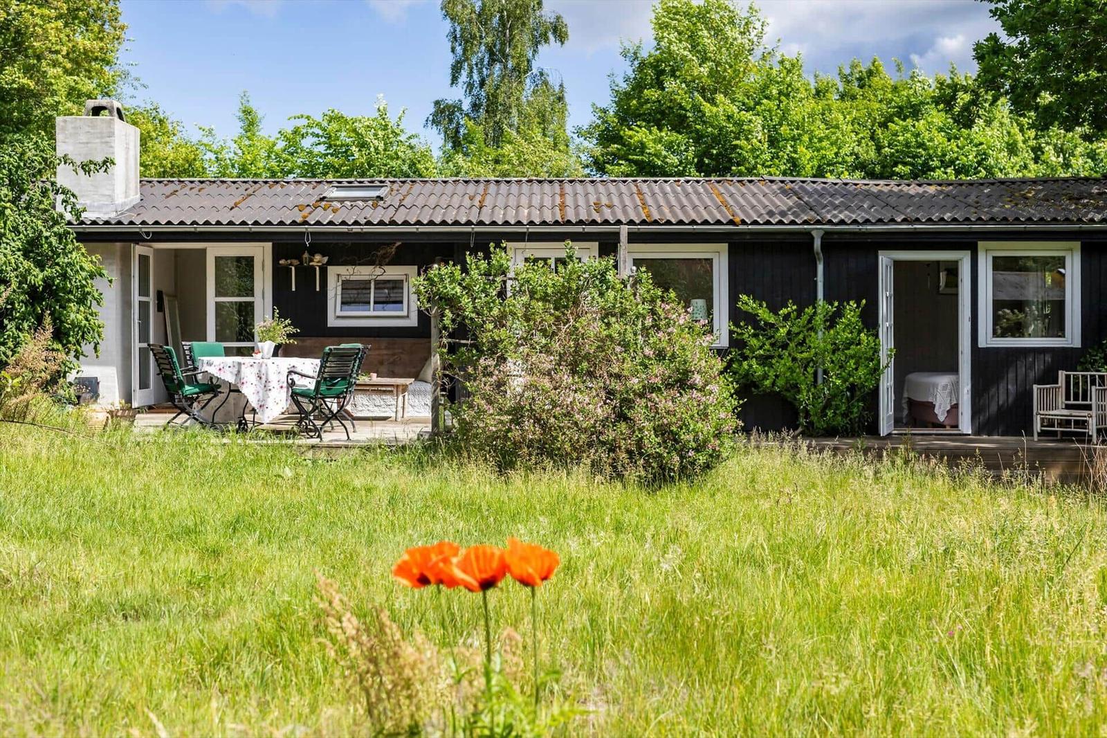 A house with a terrace, garden, and orange flowers in the foreground.
