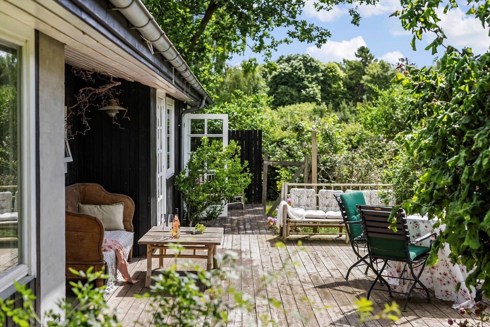 Deck with wooden planks, seating, and green surroundings.