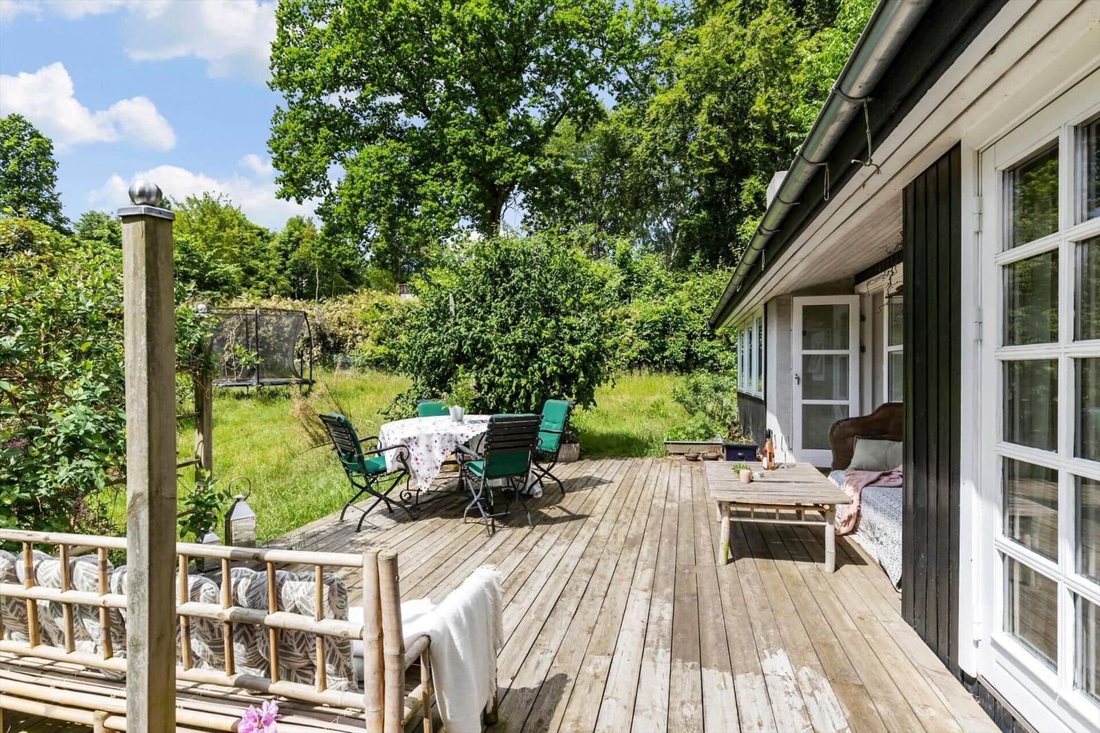 Wooden terrace with table, chairs, and garden view