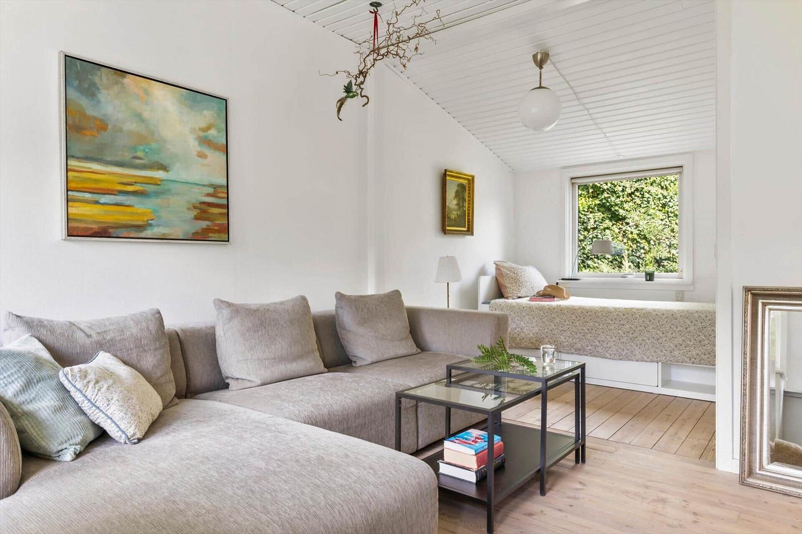 A living room with sofa, coffee table, and window view of trees.