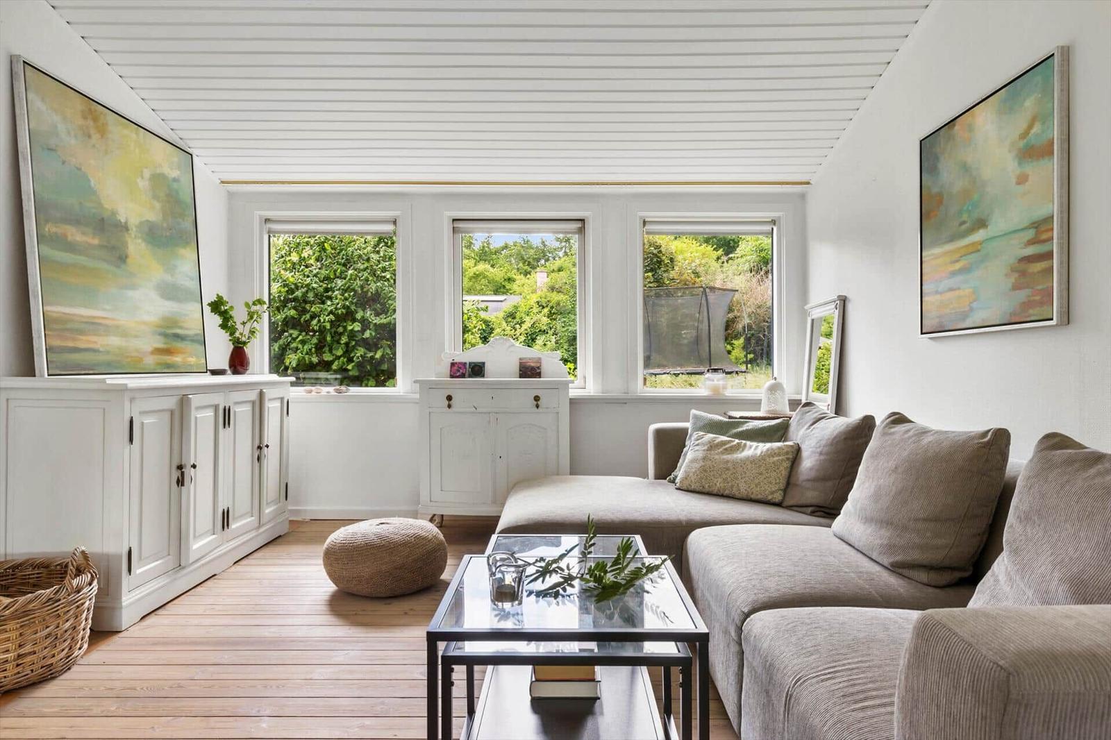 Living room with sofa, glass table, and windows to the garden.