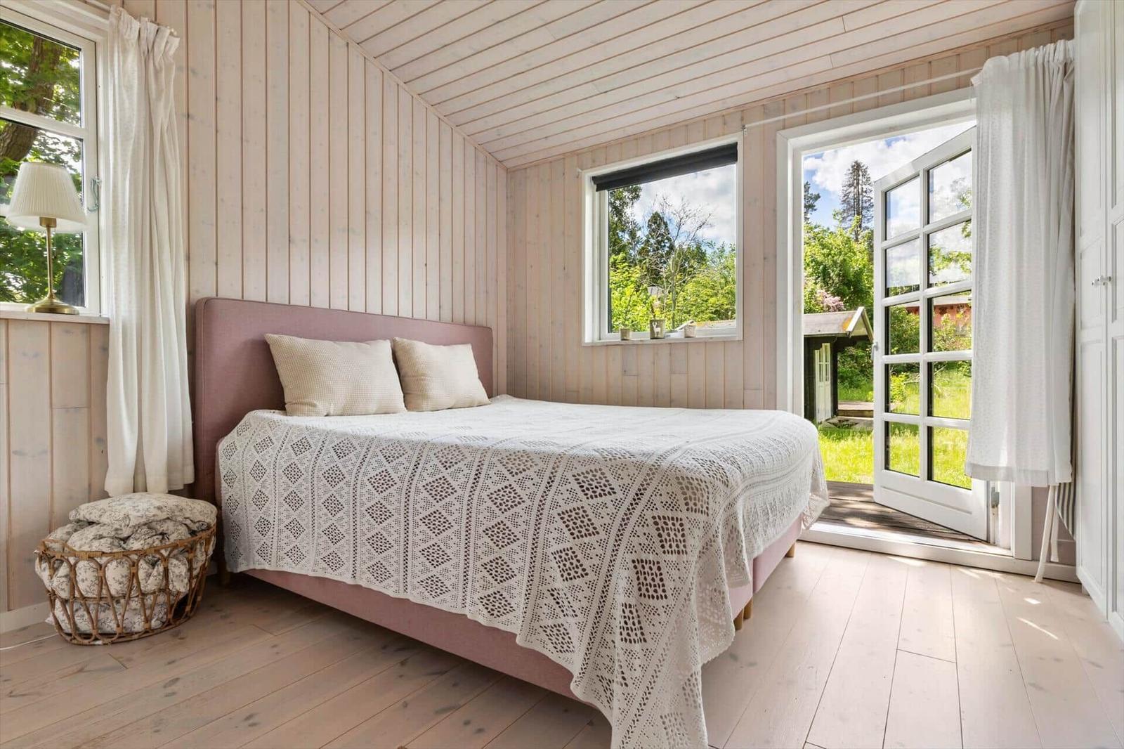 Bedroom with bed, windows, and door to outdoor terrace.