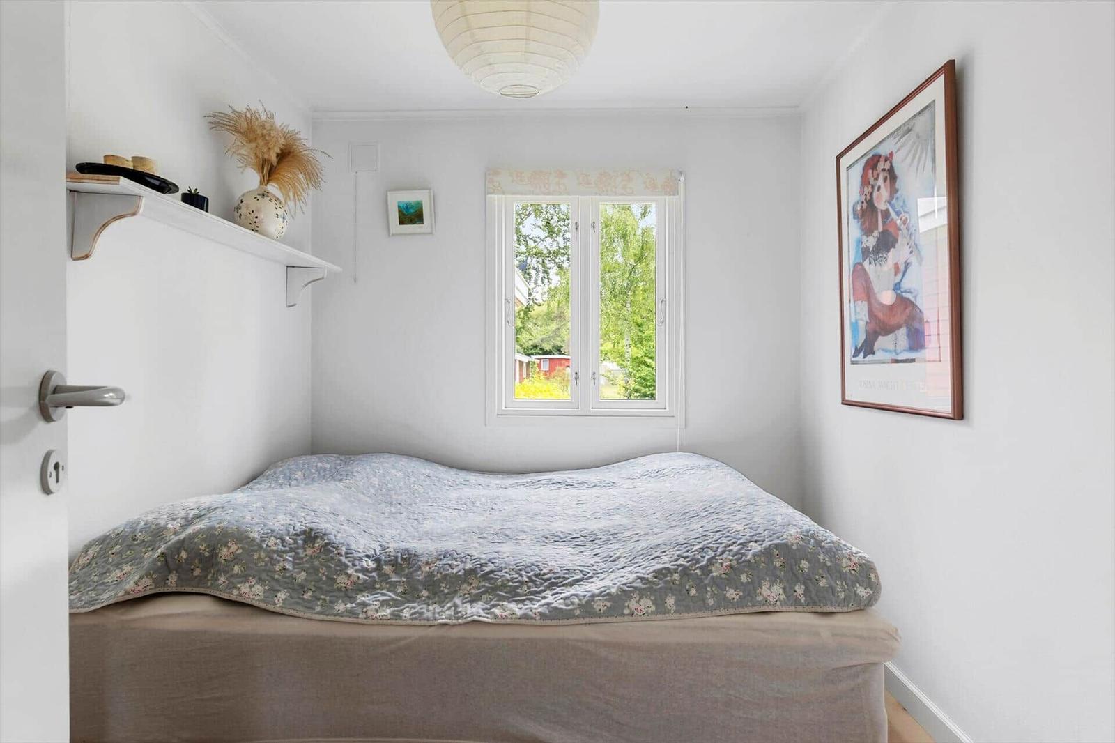Bedroom with bed, window, and wall art.