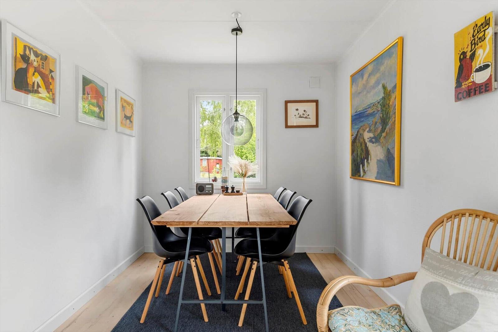 Dining room with wooden table, black chairs, and wall art
