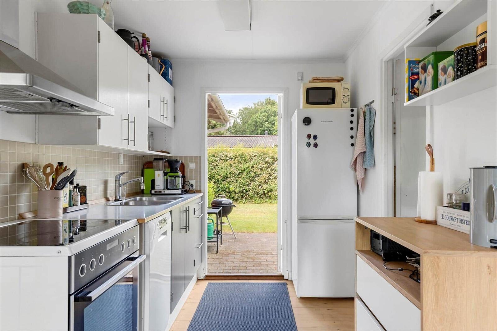 Kitchen with white built-in cabinetry, refrigerator, and view of garden.