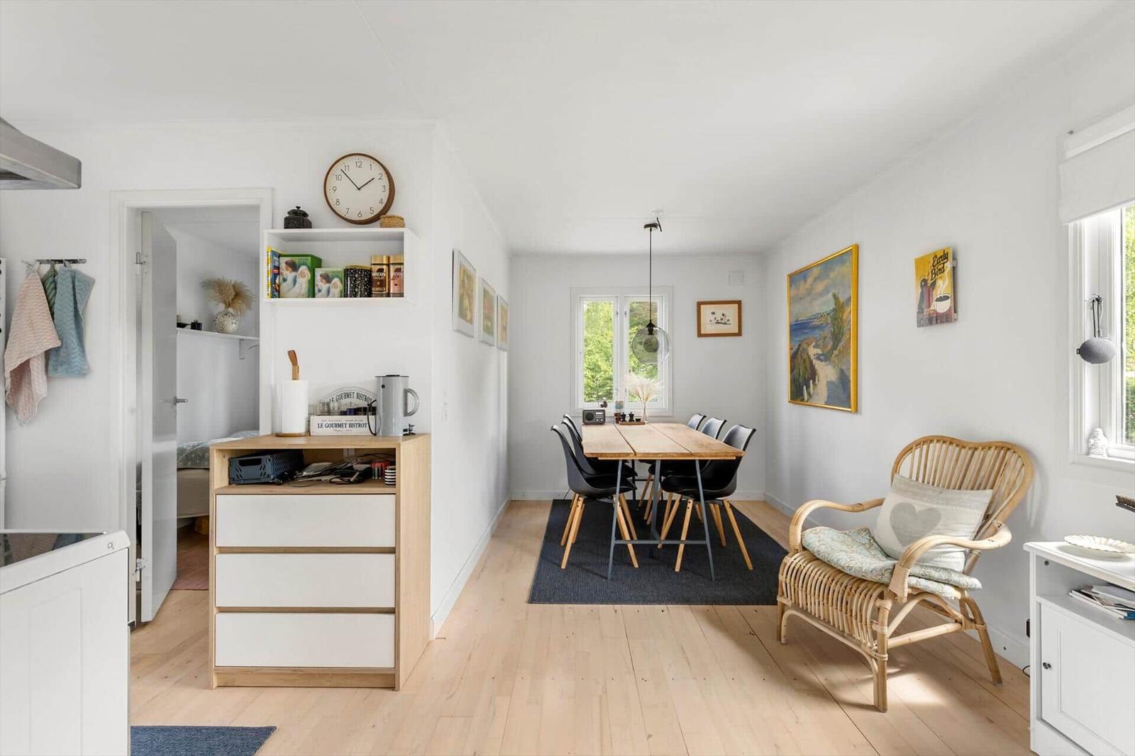 Living and dining area with wooden floor, dining table, chairs, and rattan chair.