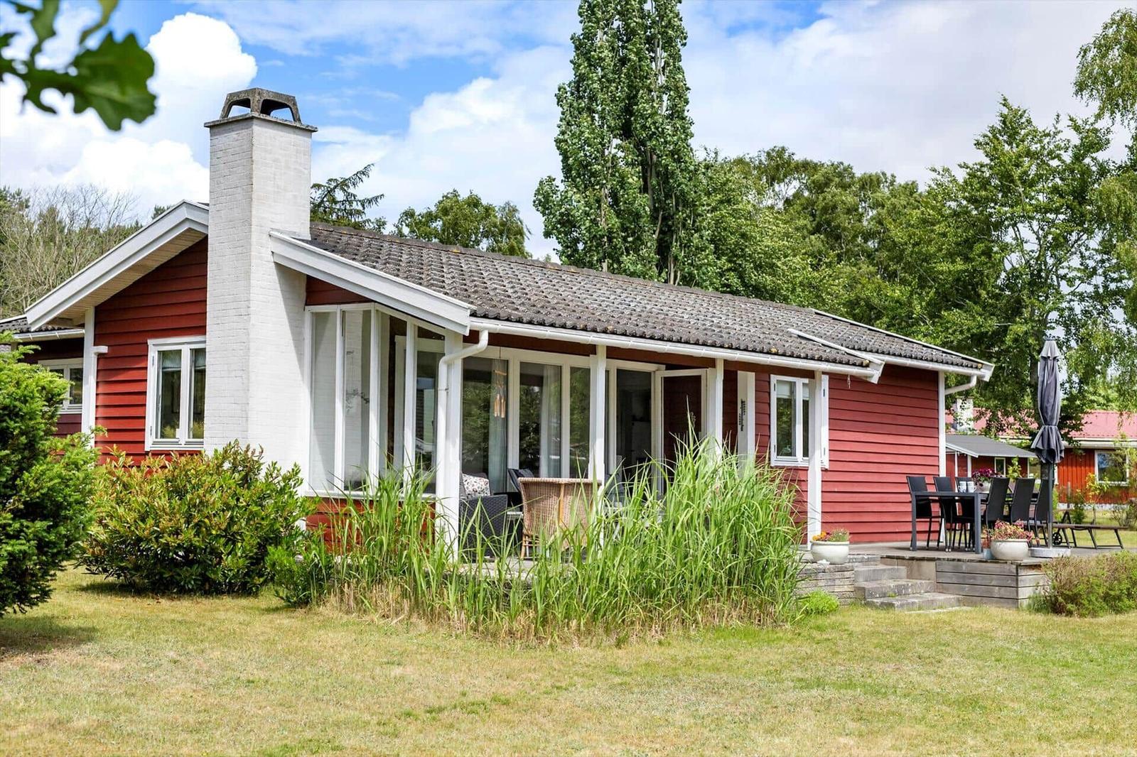 Red house with white chimney and terrace in the green
