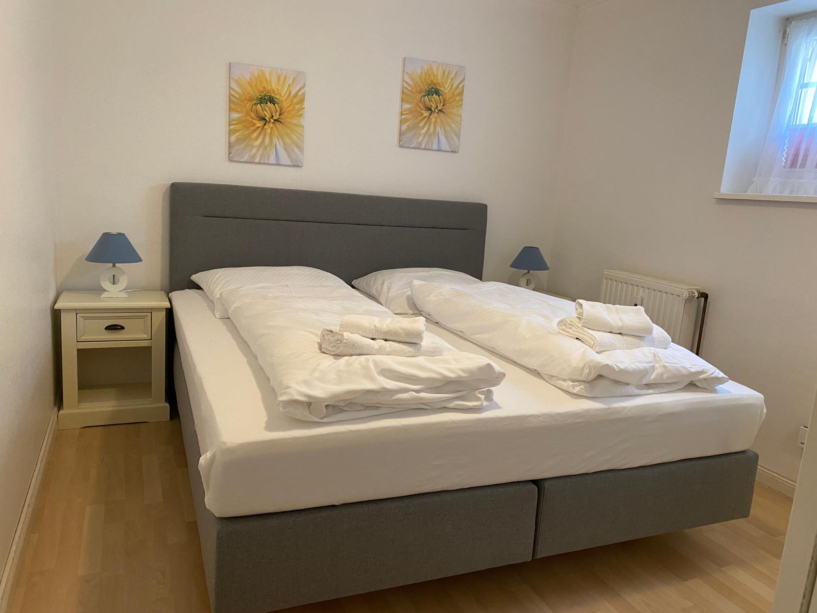 A bedroom with a double bed, two nightstands, and two wall pictures.