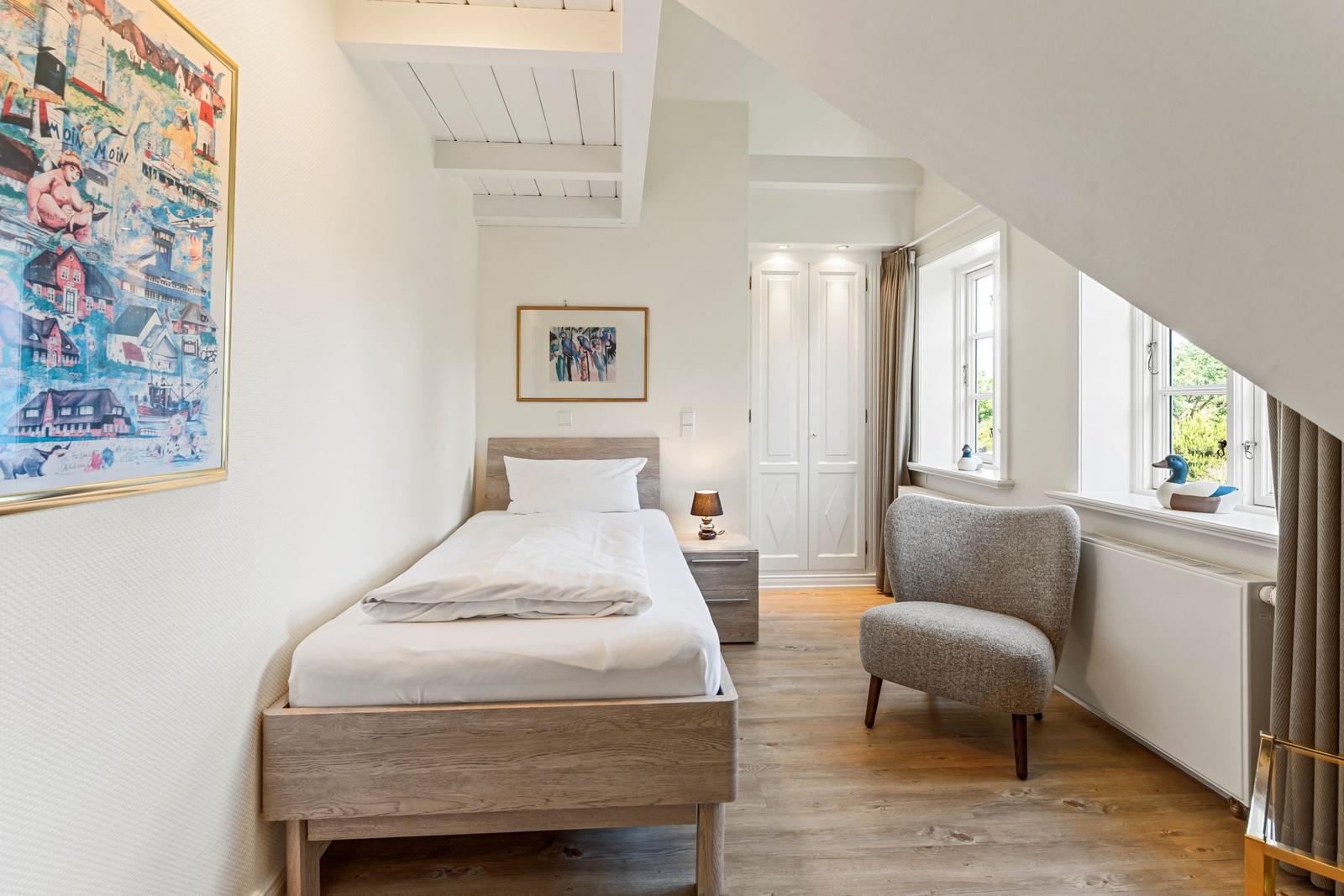 Schlafzimmer mit Bett, Stuhl und Fenster. Decke mit Balken. Wandbild und Nachttisch.