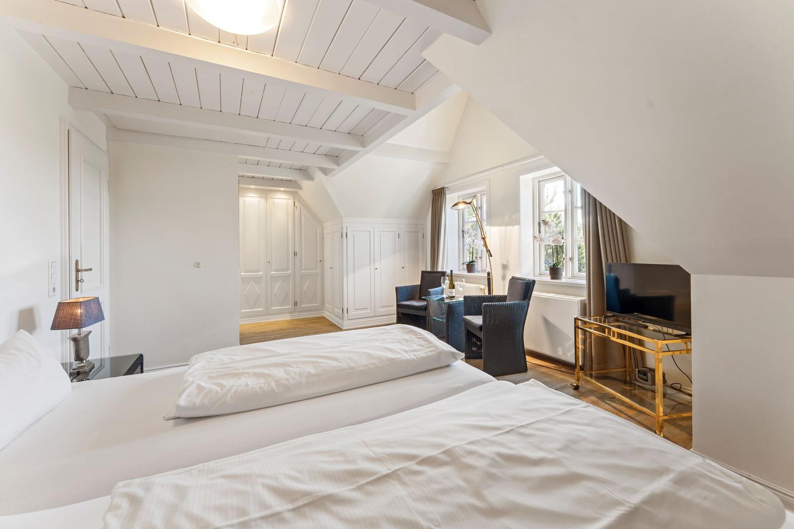 Zimmer mit Doppelbett, Schwebemöbeln und Fenster mit Blick. Deckenbalken und weißer Farbgebung.