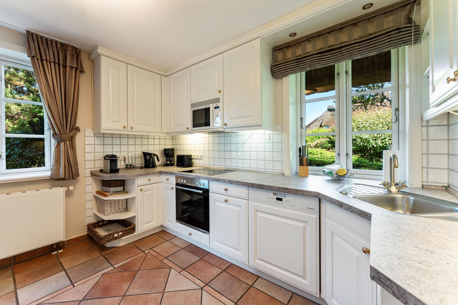 Küche mit weißen Schränken, Steinplatte und Blick auf Garten