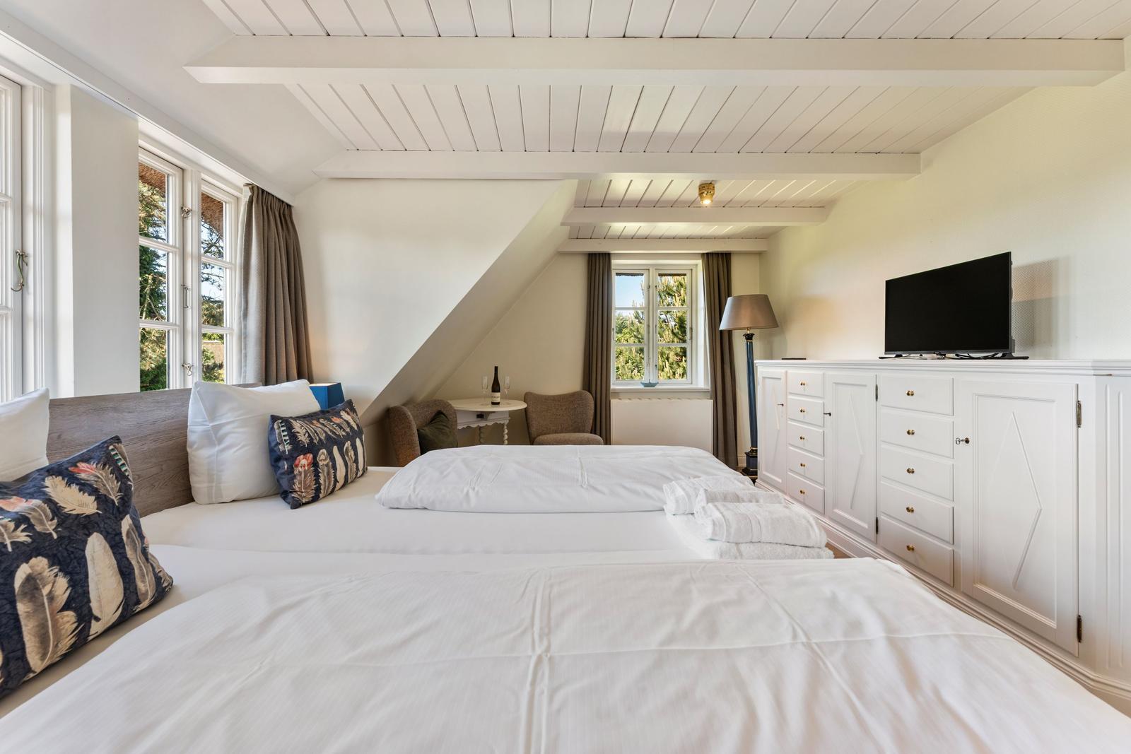 Schlafzimmer mit Doppelbett, TV und Fenster zur Aussicht.