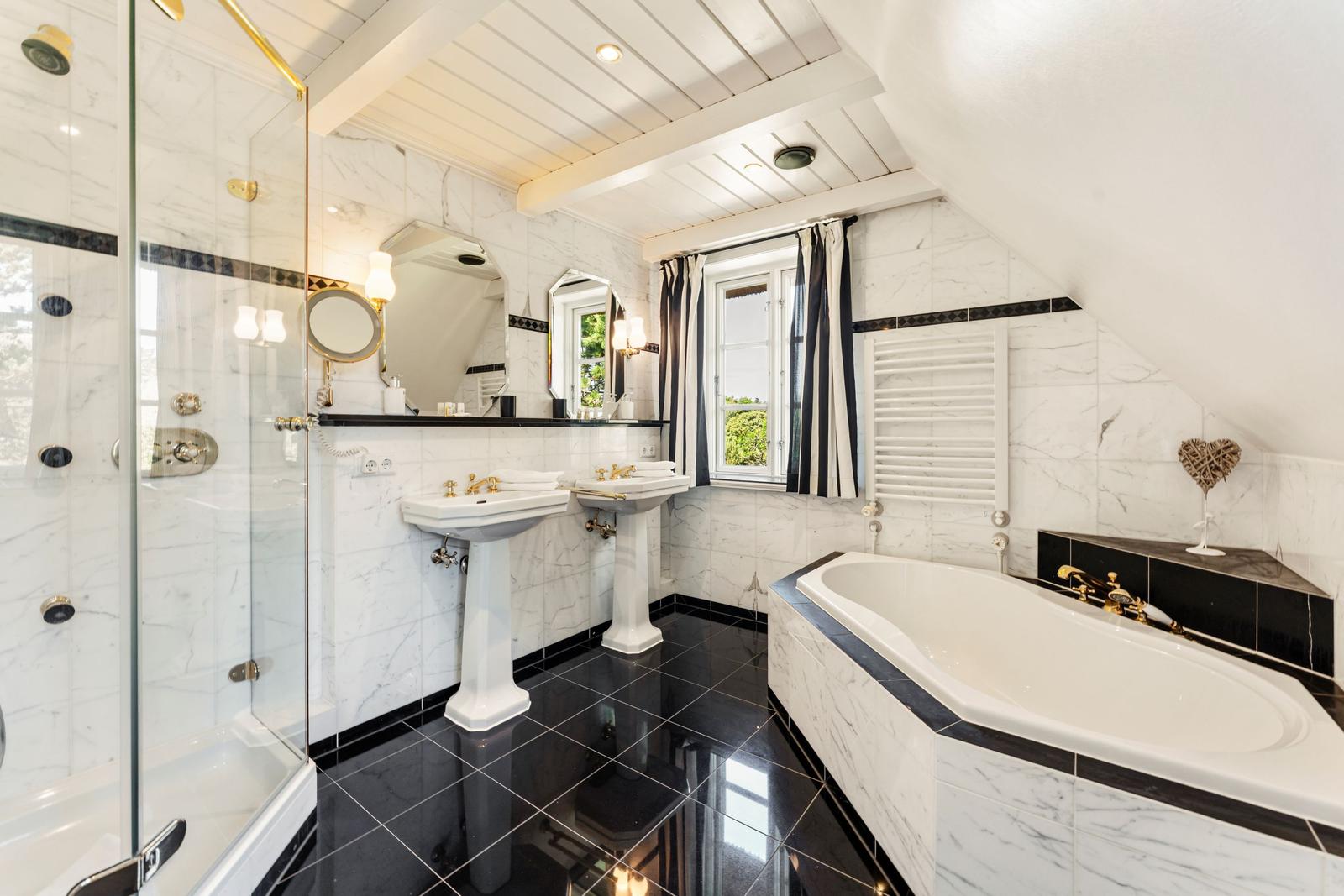 Dusche, Badewanne und zwei Waschbecken in einem Badezimmer mit schwarz-weißem Marmor.