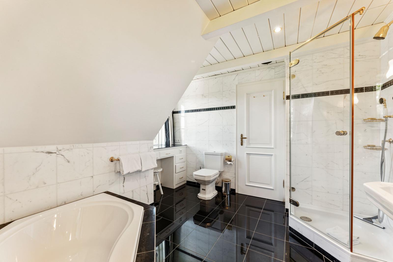 Badezimmer mit Badewanne, Dusche und Toilette unter schrägem Dach