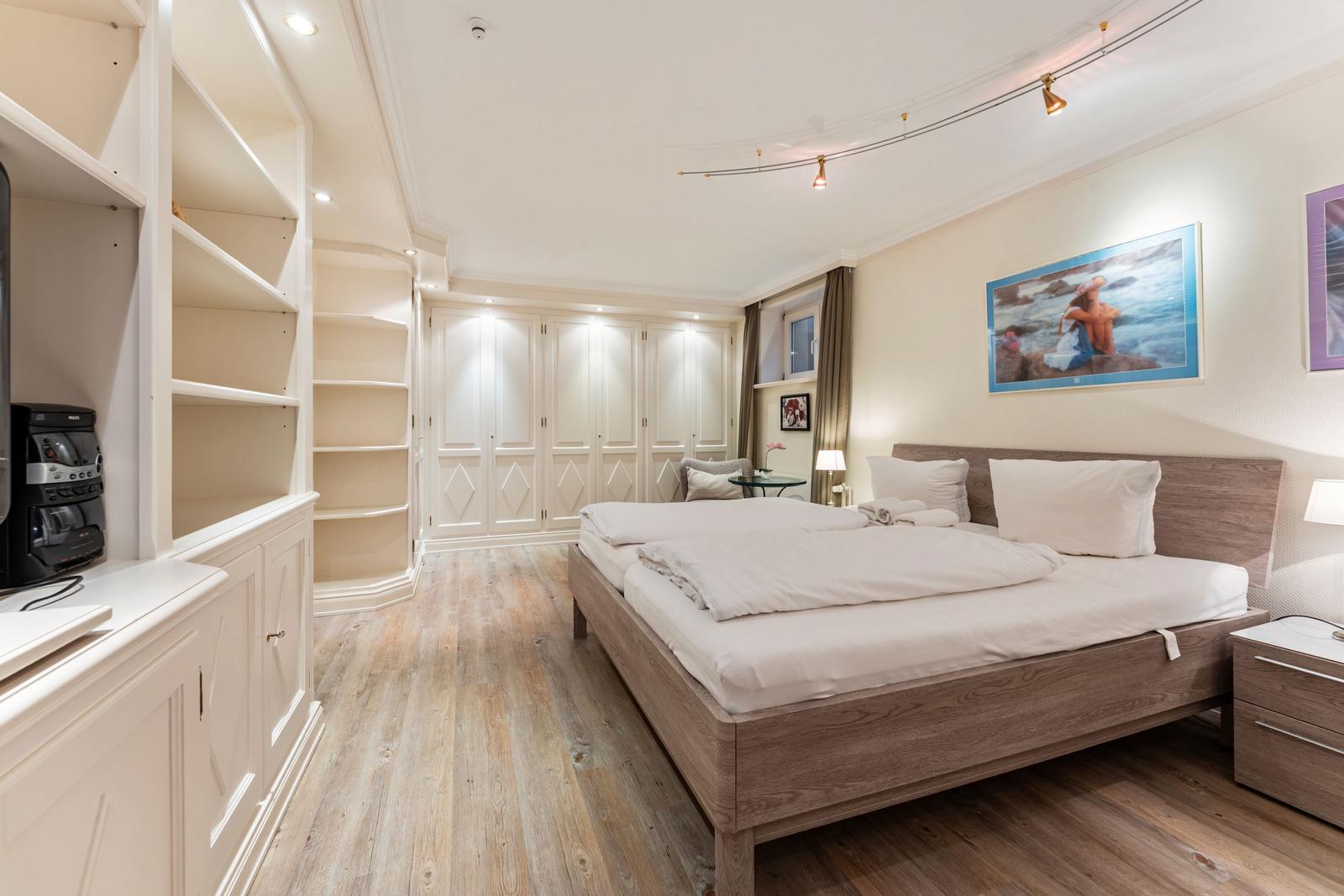 Schlafzimmer mit Doppelbett, Kleiderschrank und Holzboden.