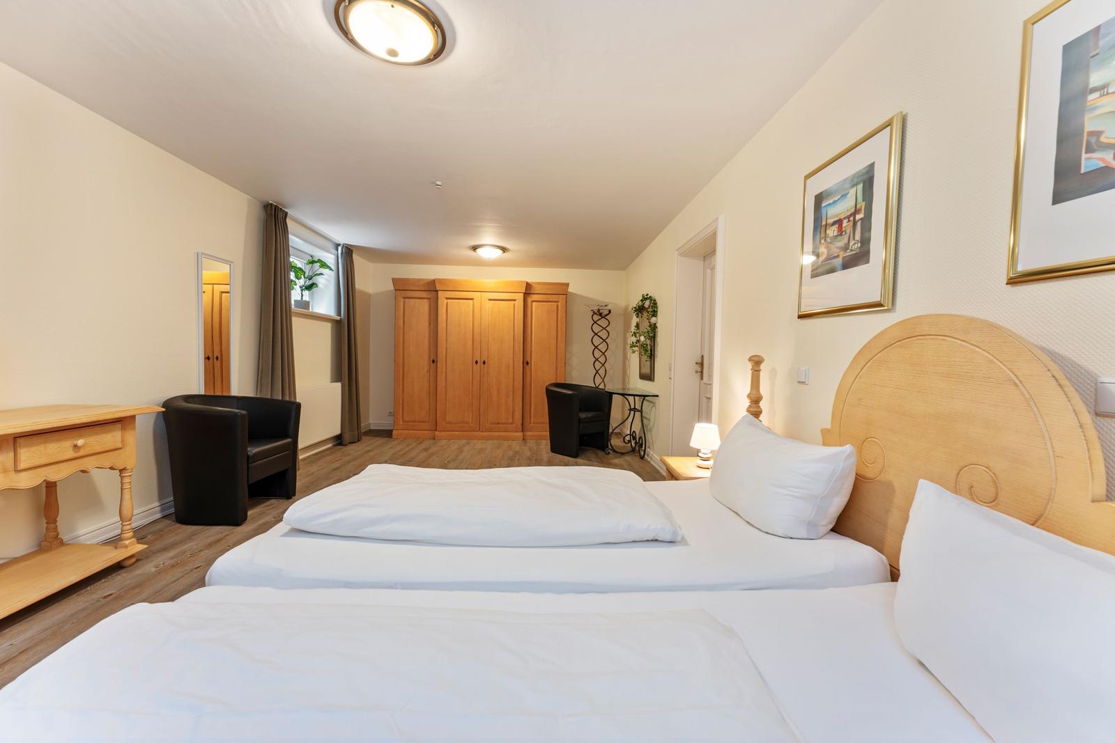 Schlafzimmer mit Doppelbett, Kleiderschrank und Sitzgelegenheit.