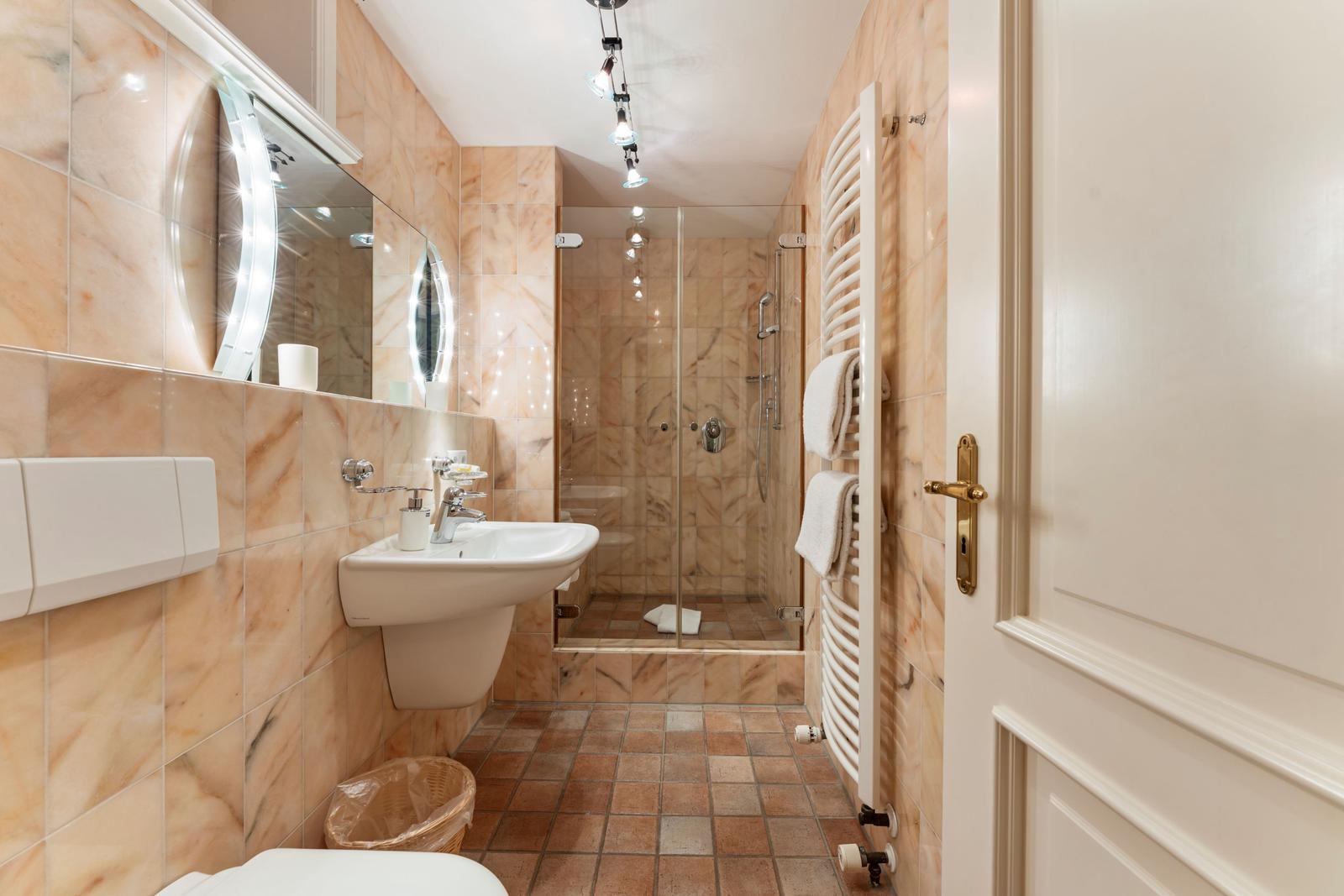 Badezimmer mit Dusche, Waschbecken und Heizkörper an Wand