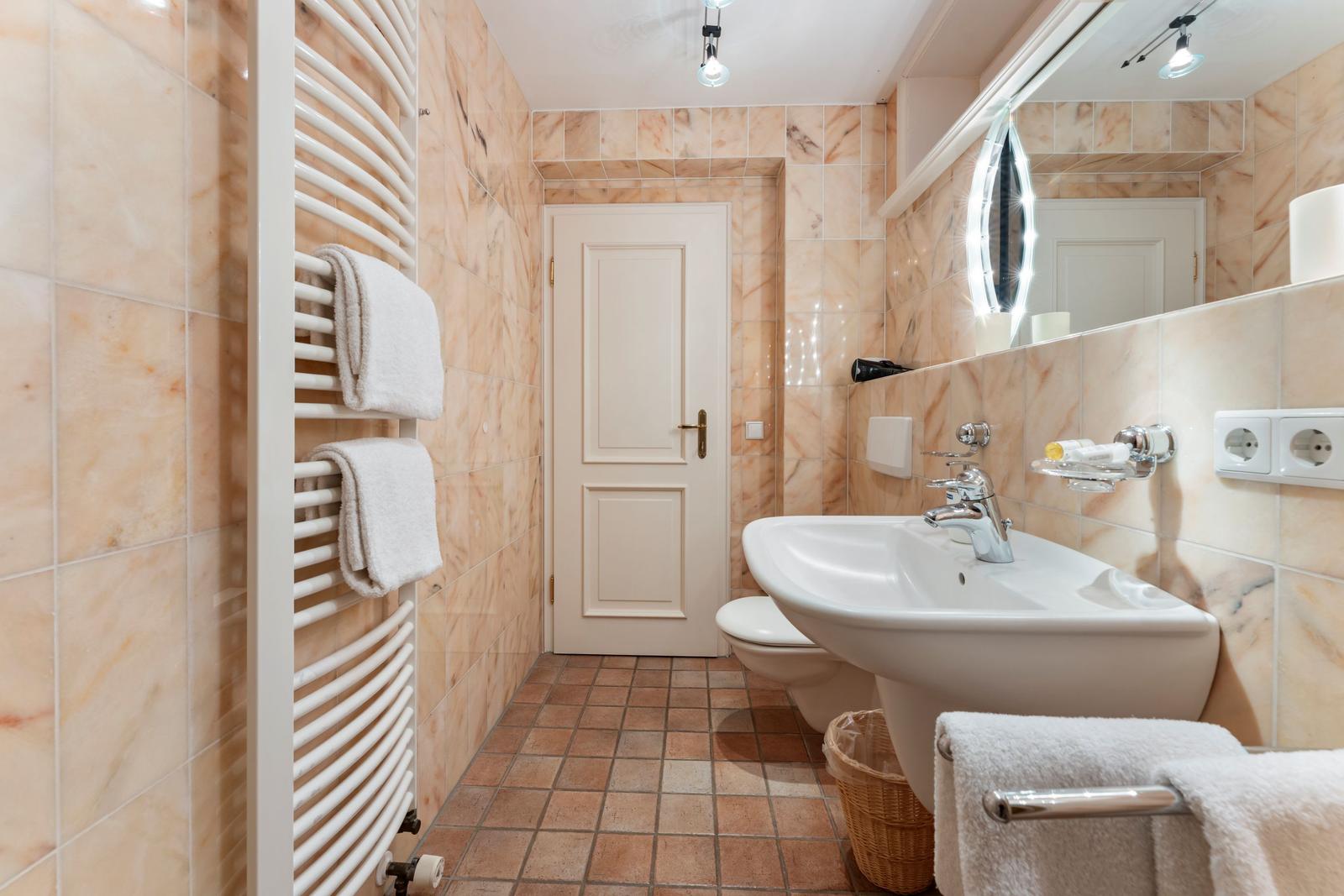 Badezimmer mit Waschbecken, Toilette, Heizung und Spiegel