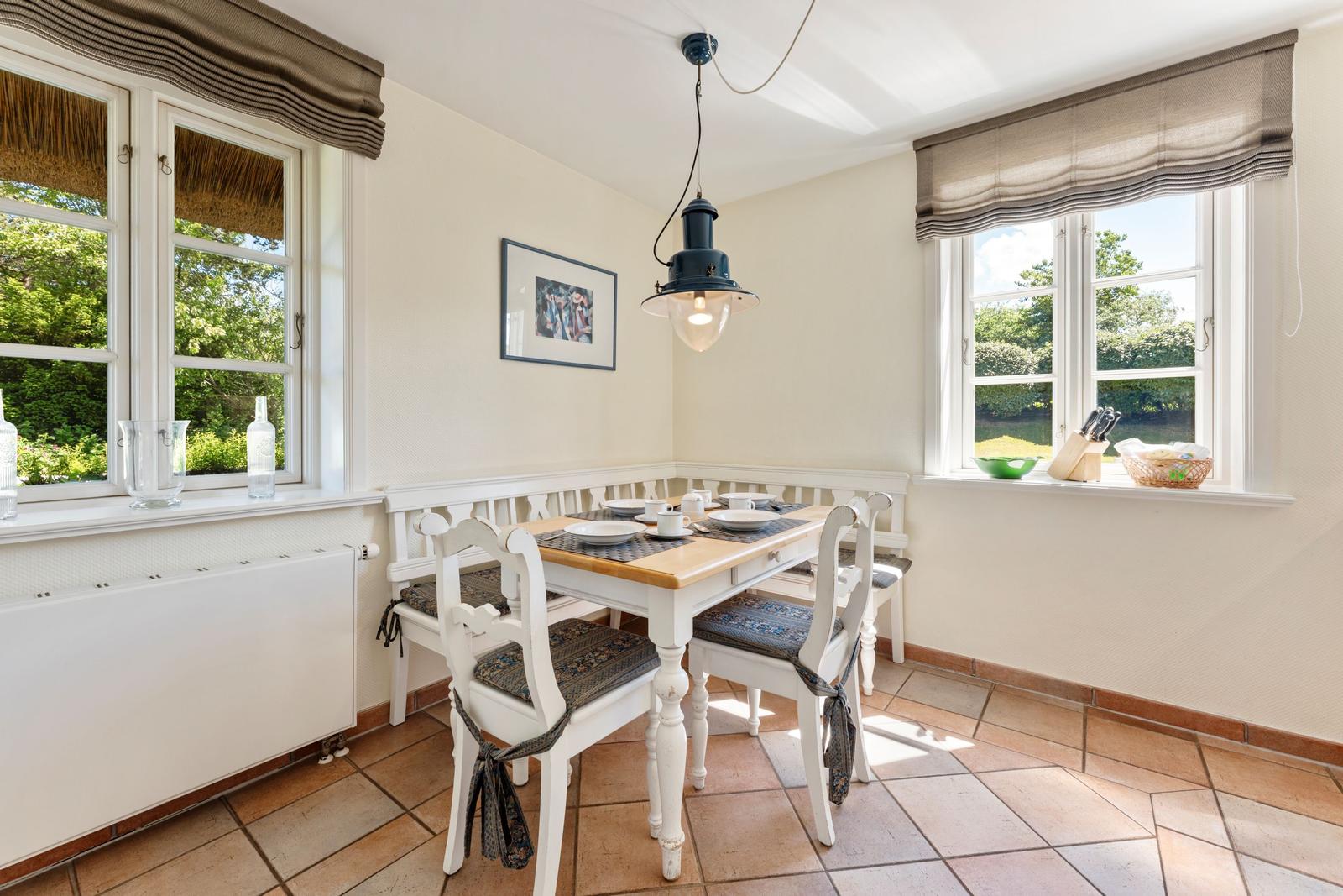 Esszimmer mit Tisch, Stühlen und Fenstern zum Garten.