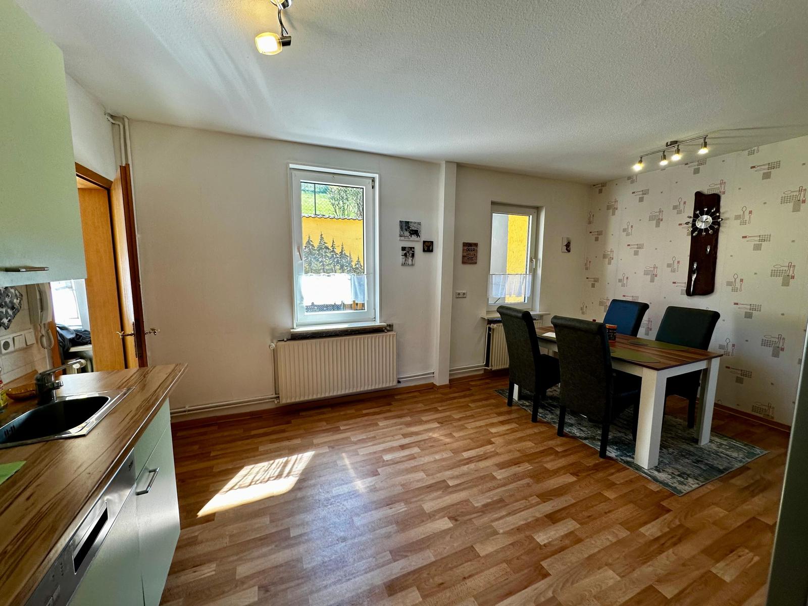 Küche mit Essbereich, Holzboden und Fenster mit Blick auf Außengebiet.