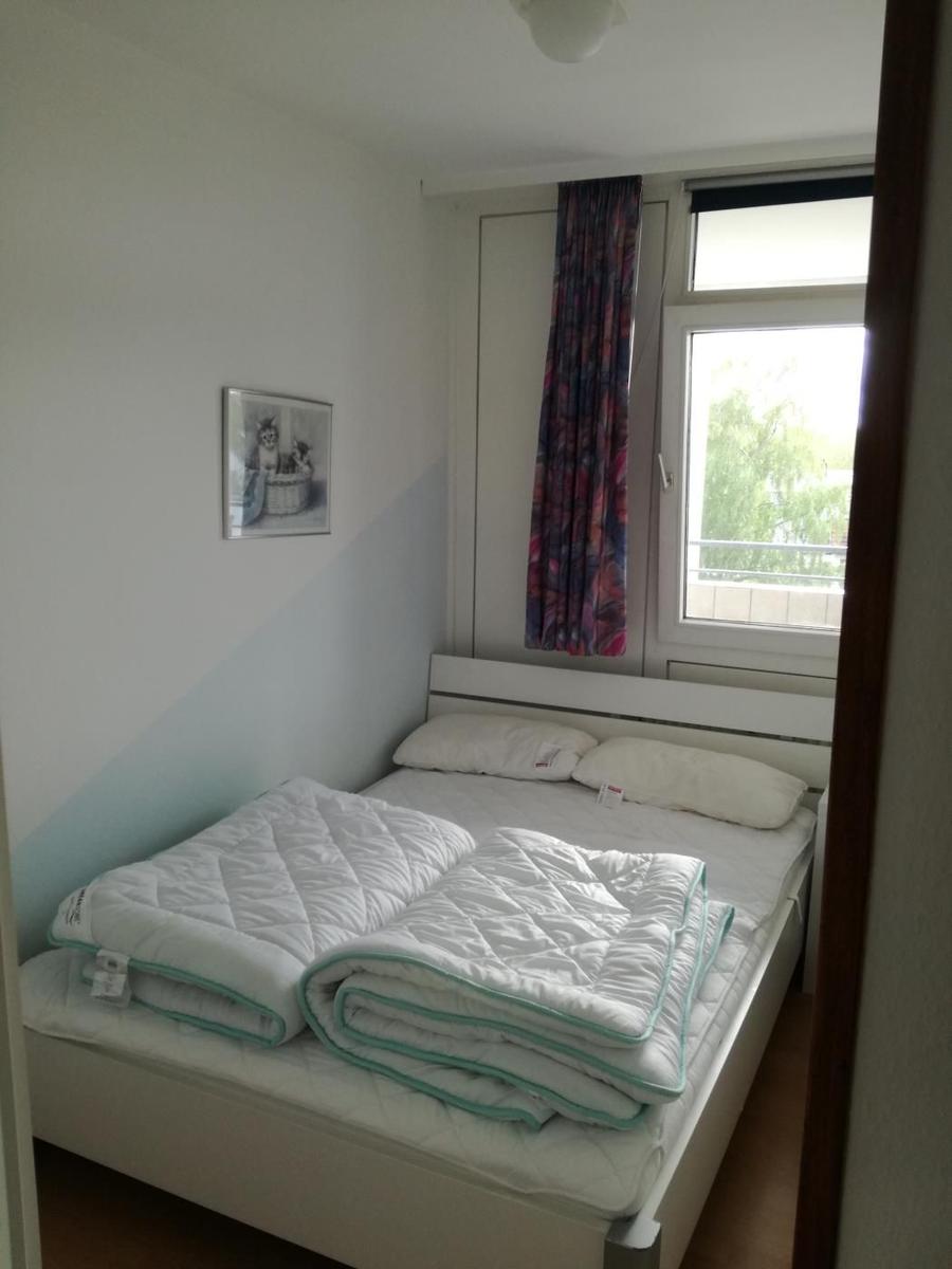 Schlafzimmer mit Doppelbett, Fenster und Vorhang.