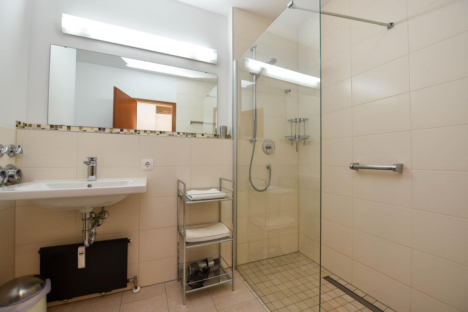 Badezimmer mit Dusche, Waschbecken und Spiegel