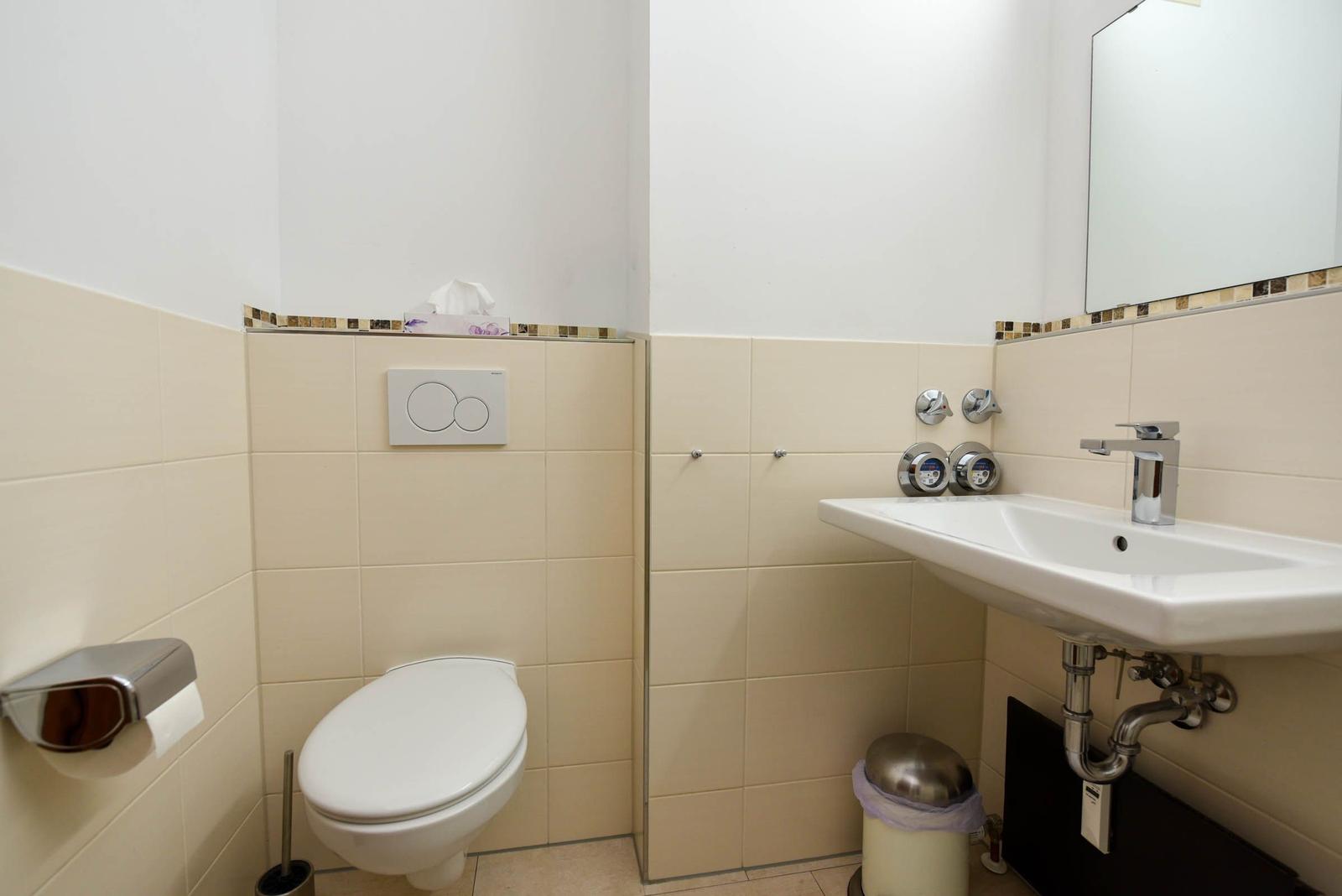Badezimmer mit Toilette, Waschbecken und Spiegel