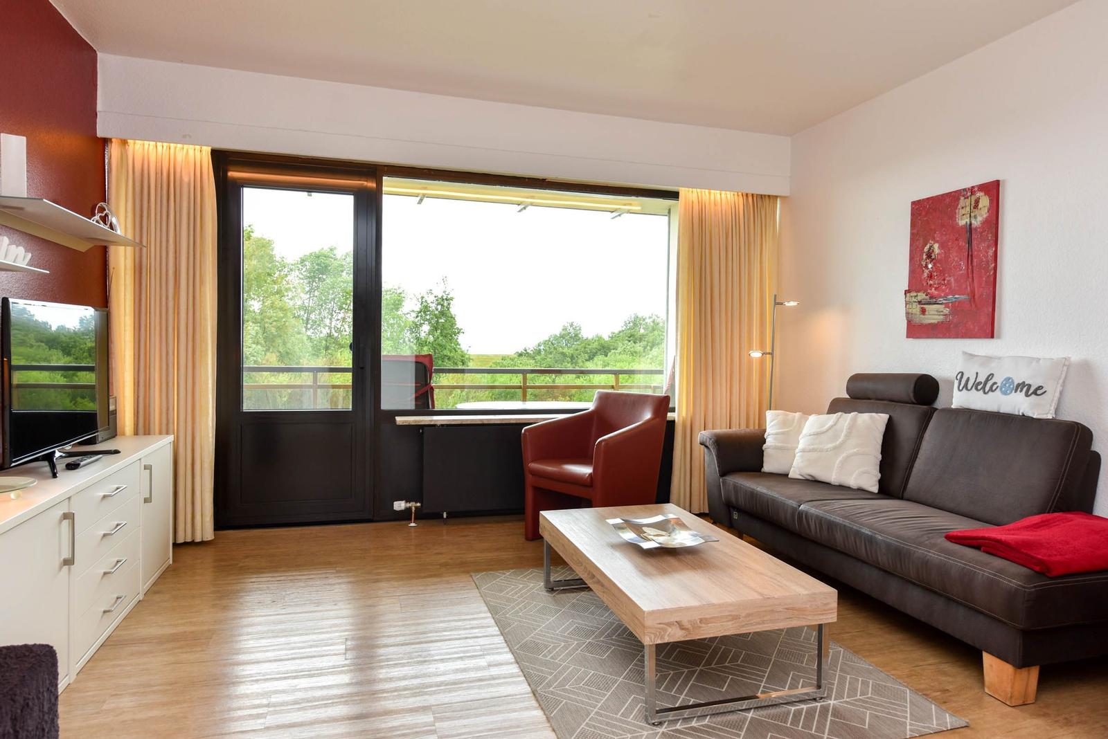 Wohnzimmer mit Sofa, Sitzgelegenheit und Balkonansicht.