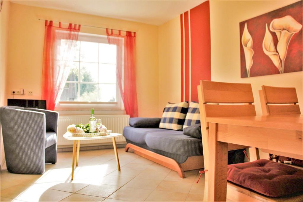 Living area with sofa, table, chairs, and window with red curtains.