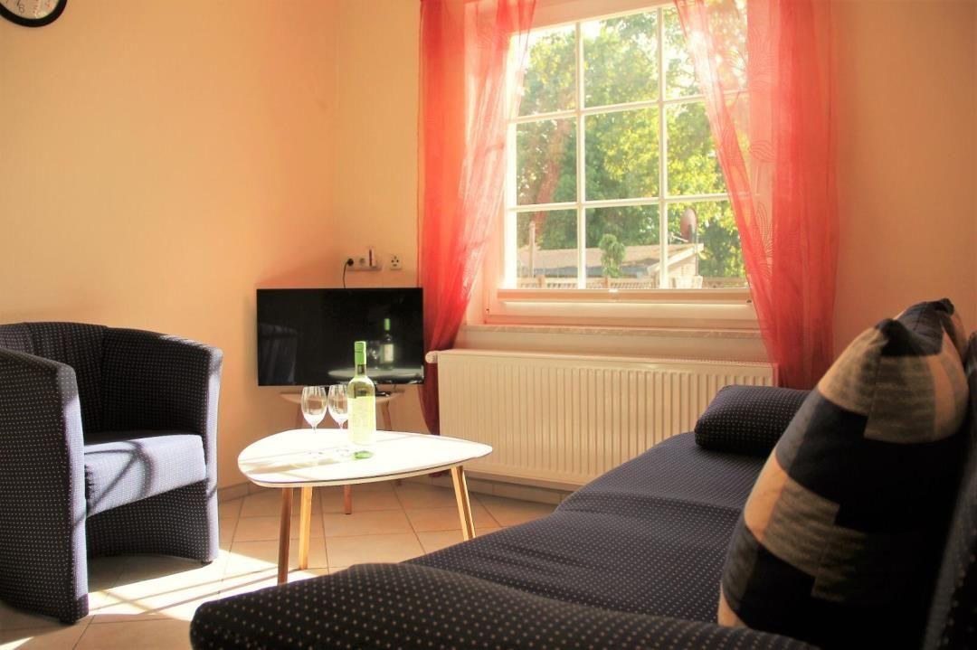 Living room with sofa, armchair, table, TV, and window with red curtains.