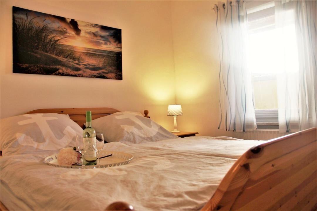 A bed with a wooden frame, a picture on the wall, and a window with curtains.
