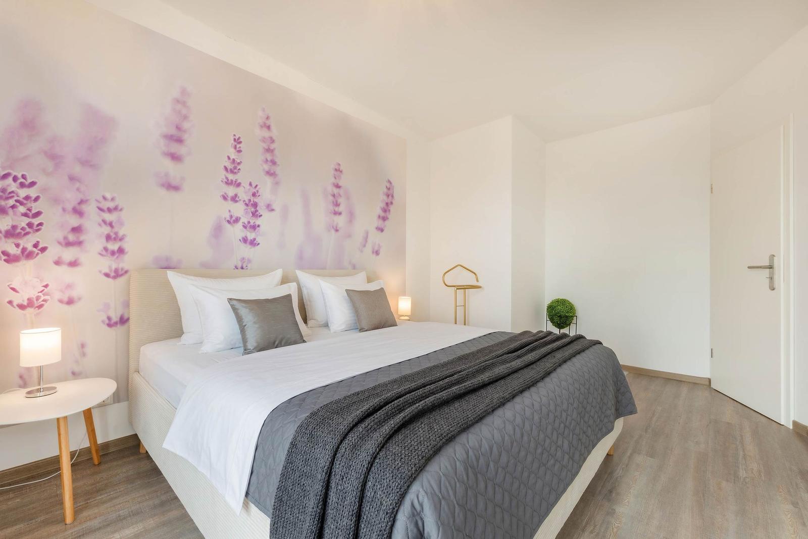 Schlafzimmer mit Bett, Wandbild und Nachttisch.