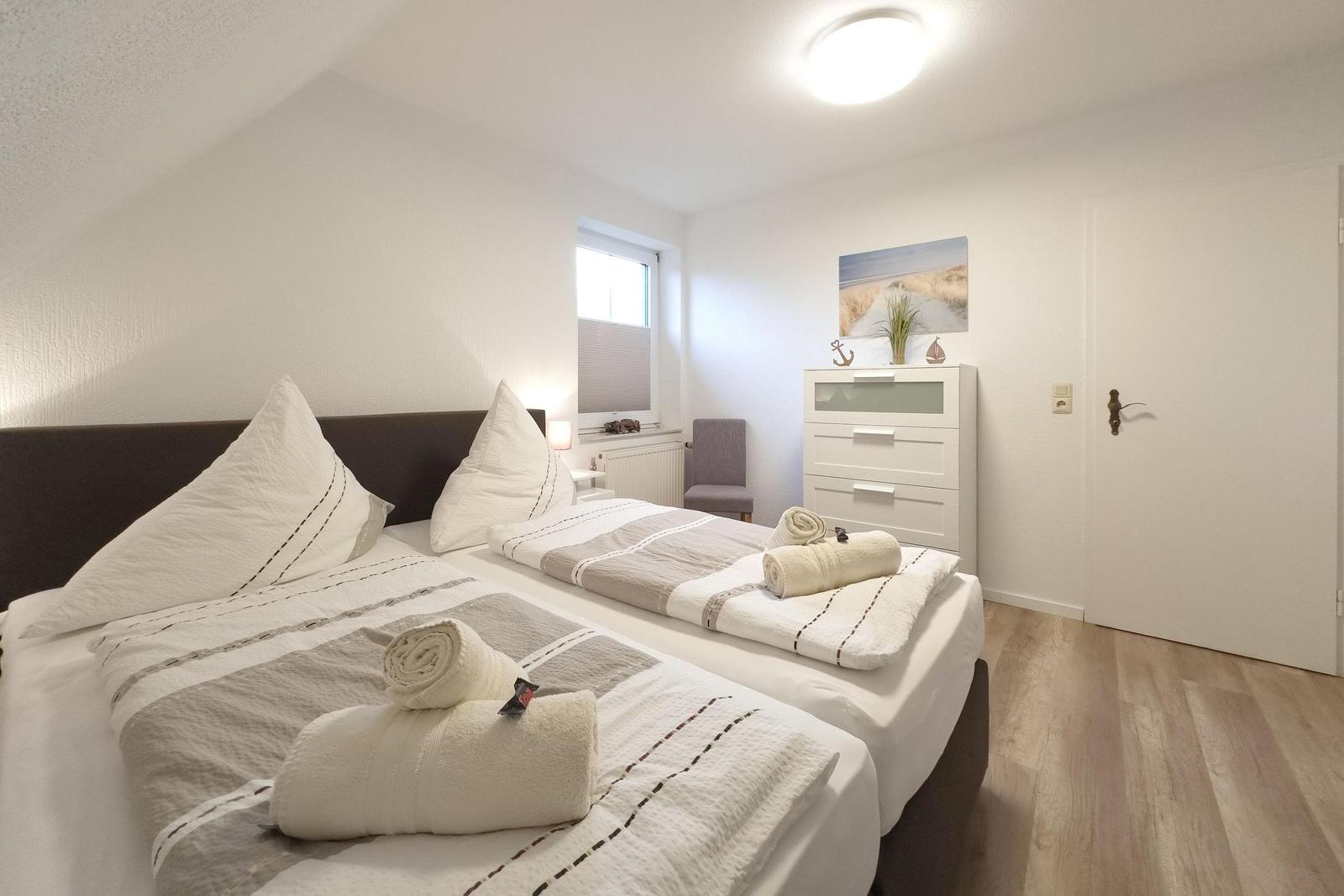 Zimmer mit Doppelbett, Schrank, Fenster und Holzboden.