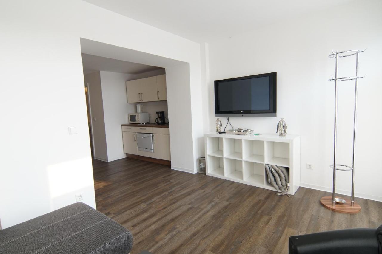 Wohnbereich mit TV, Schrank und Küchenbereich im Hintergrund.