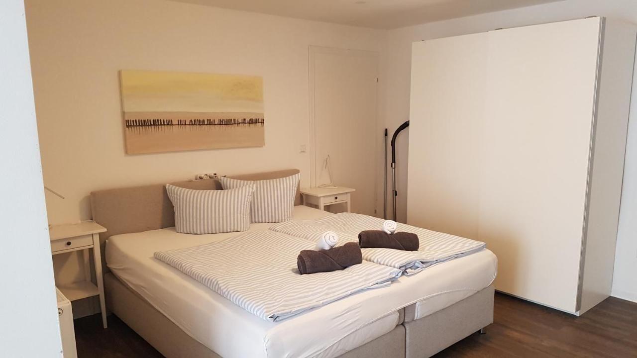 Schlafzimmer mit Doppelbett, zwei Nachttischen und Kleiderschrank. Auf dem Bett liegen gefaltete Handtücher.