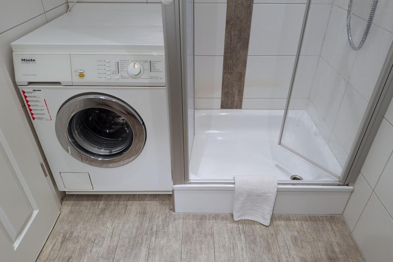 Waschmaschine neben Dusche mit Handtuch