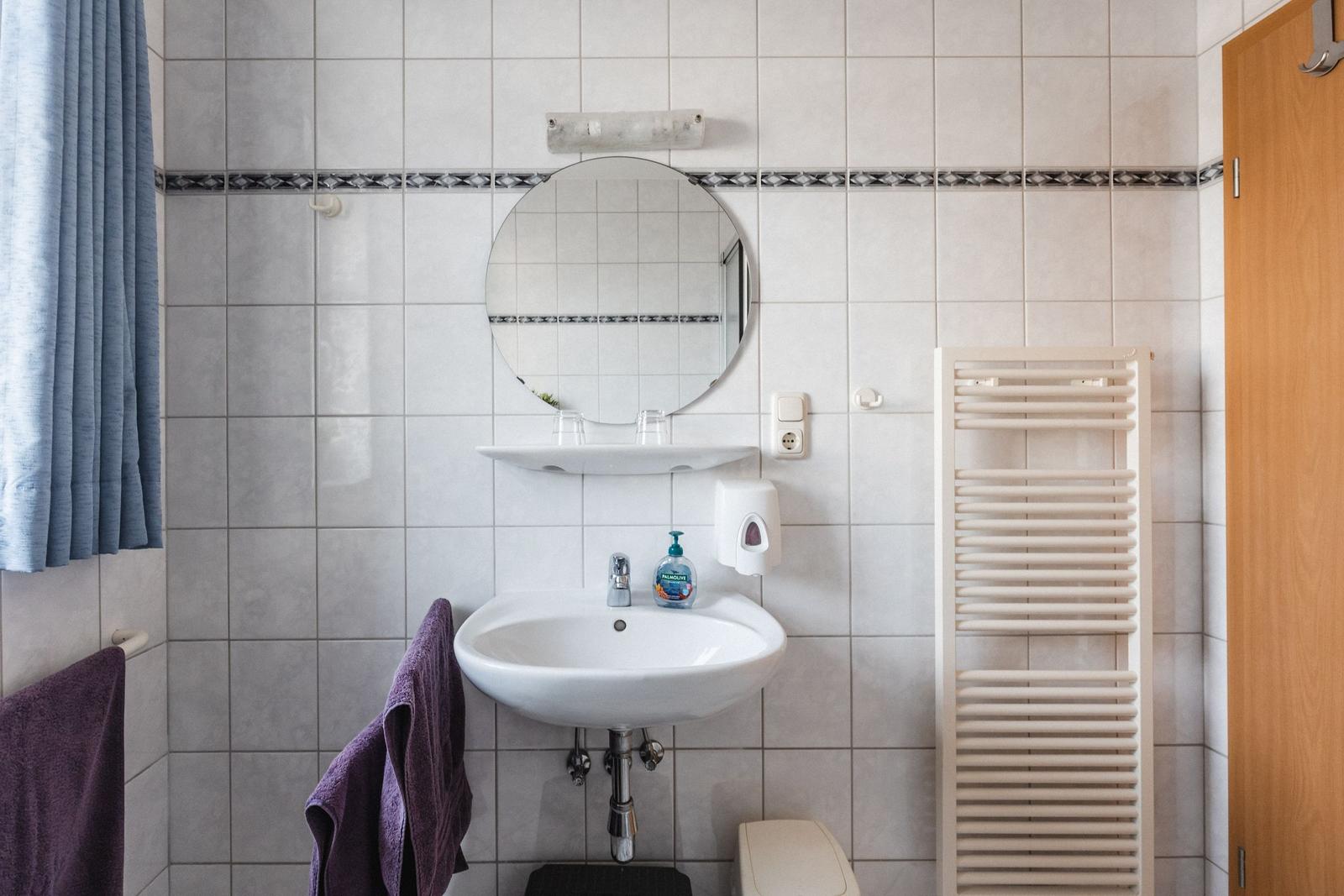 Badezimmer mit Waschbecken, Spiegel und Handtuchhalter