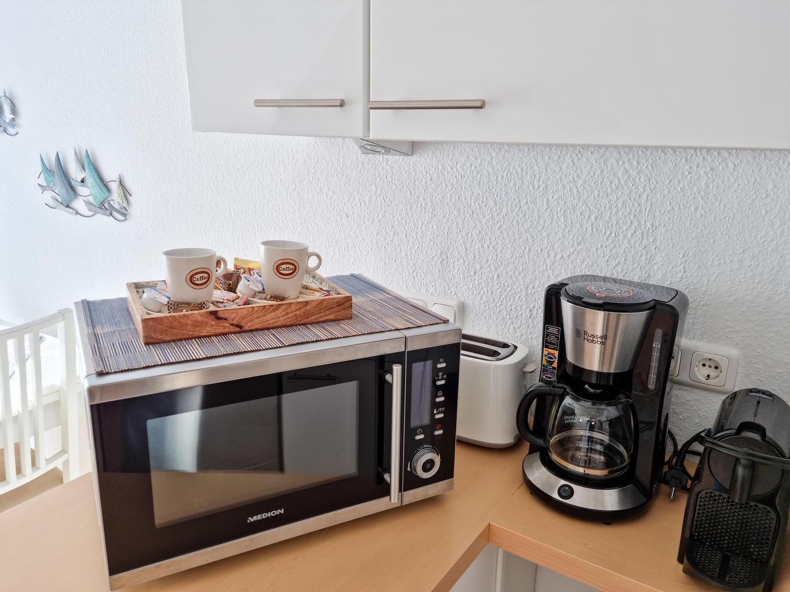 Küchenbereich mit Mikrowelle, Kaffeemaschine und Toaster auf Arbeitsfläche.