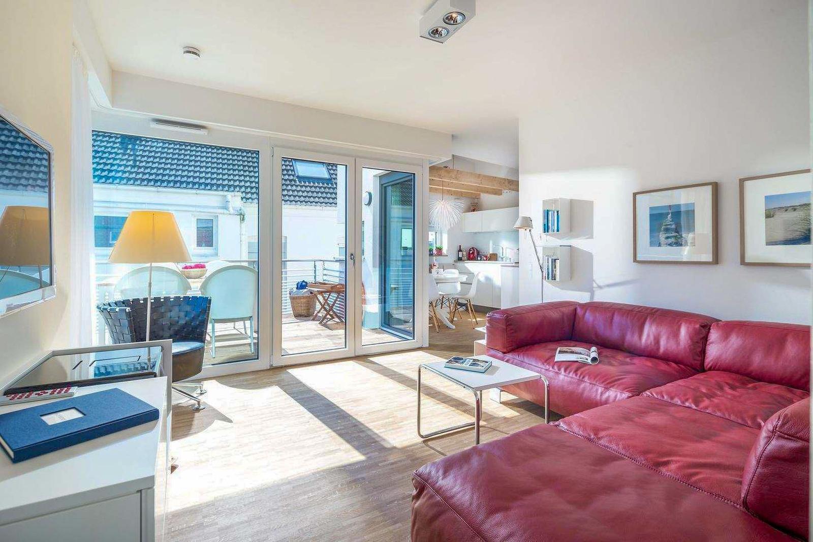 Wohnzimmer mit rotem Sofa, Terrasse und Küchenbereich