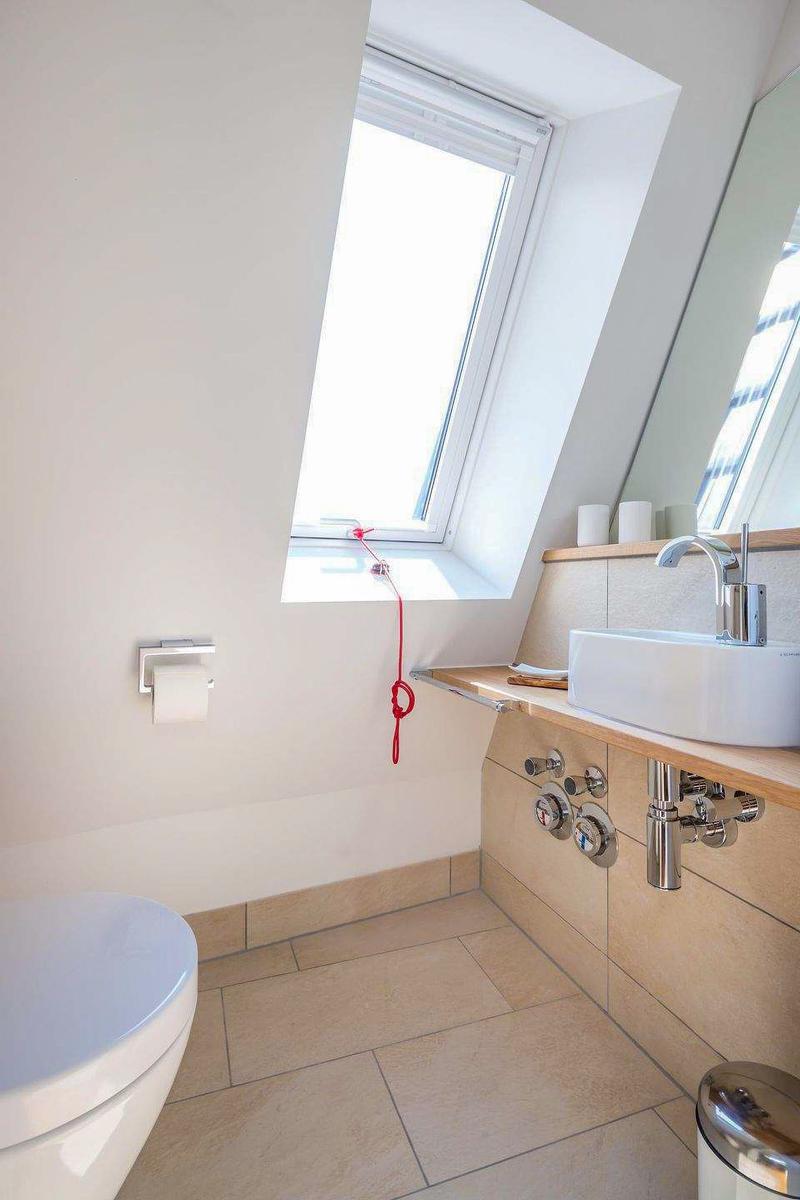 Badezimmer mit Dachfenster, Waschbecken und Toilette.