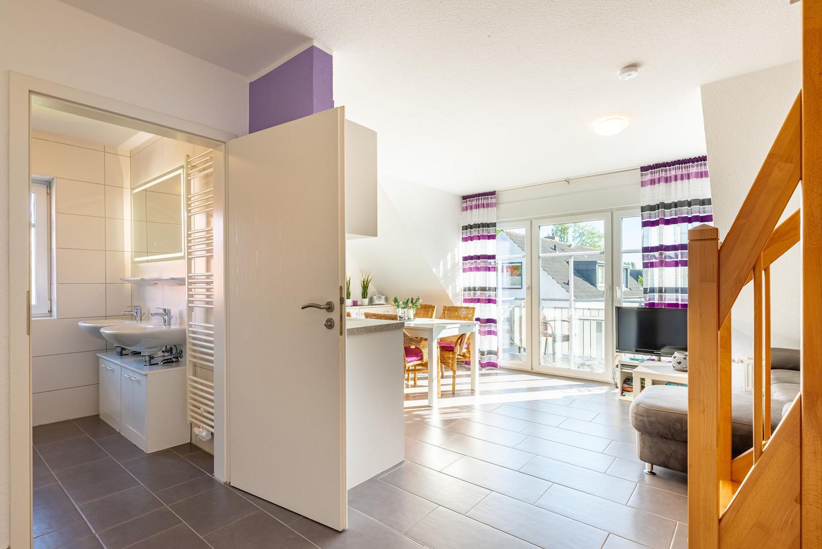 Wohnung mit Küche, Essbereich und Bad. Durchgang zur Terrasse mit Glasfront.
