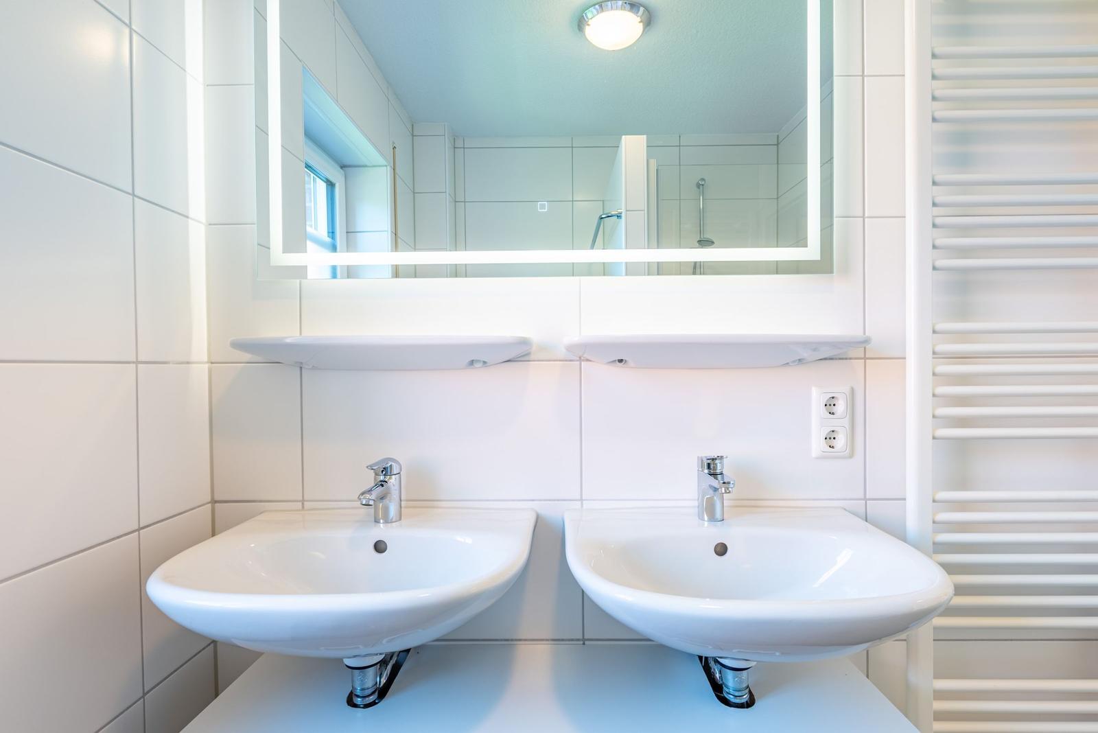 Zwei Waschbecken mit Spiegeln und Heizkörper an der Wand