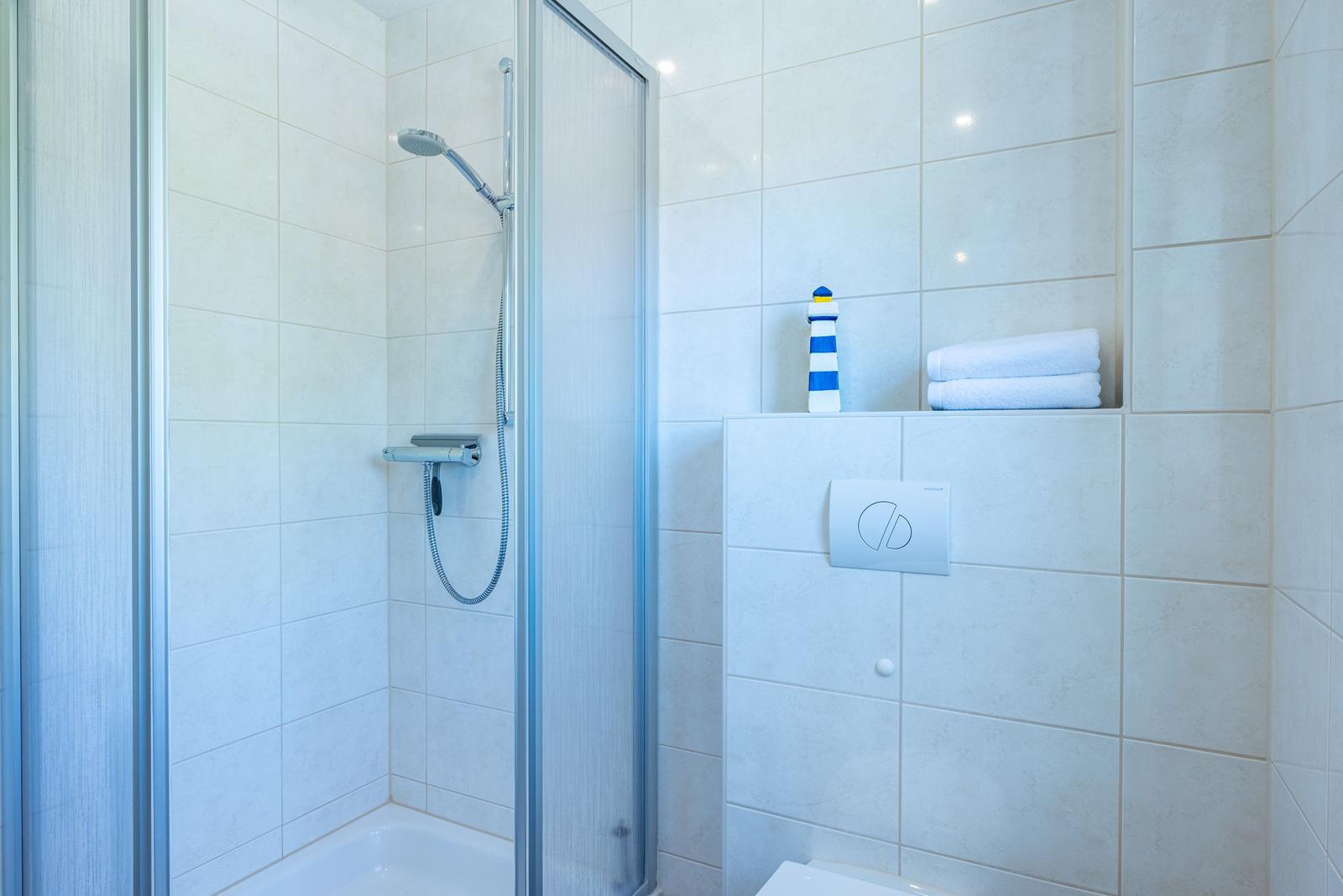 Dusche mit Duschbrause, Handtuch und Leuchtturm-Dekoration