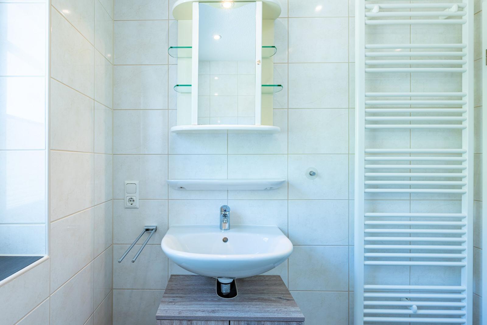 Badezimmer mit Waschbecken, Spiegelschrank und Heizkörper