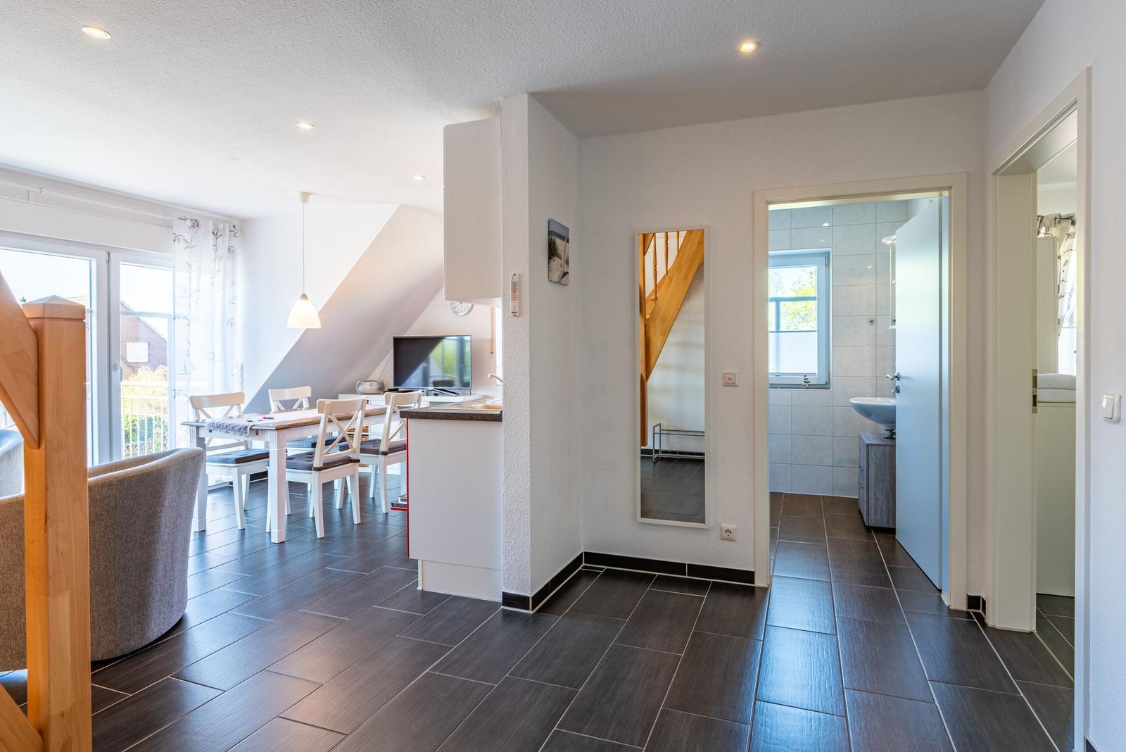 Wohnung mit Essbereich, Küche und Bad. Holzboden und Fenster zur Terrasse.