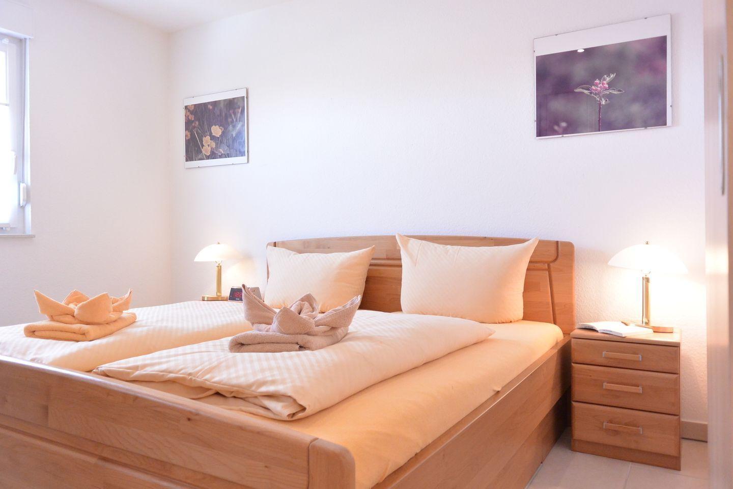 Schlafzimmer mit Holzbett, zwei Nachttischen und Bildern an der Wand.